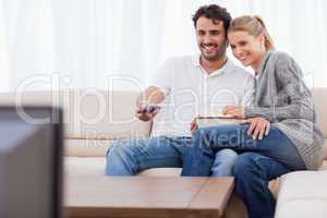 In love couple watching TV while eating popcorn