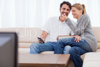 Lovely couple watching TV while eating popcorn