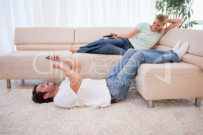 Woman watching television while her boyfriend is using his cellp