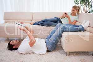 Woman using her smartphone while her boyfriend is using a tablet