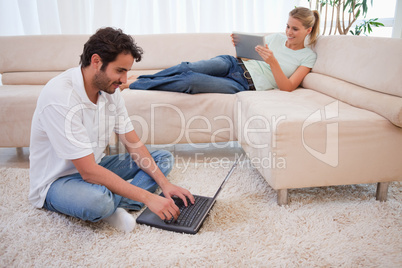 Woman using a tablet computer while her husband is using a lapto
