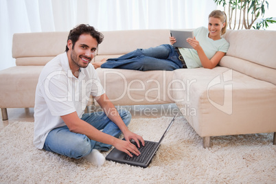 Woman using a tablet computer while her boyfriend is using a not