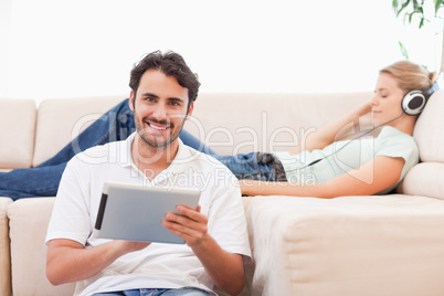 Man using a tablet computer while his wife is listening to music
