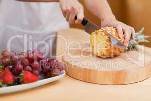 Close up of young feminine hands slicing a pineapple