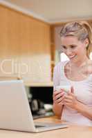 Portrait of a young woman using a laptop while drinking coffee