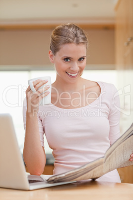 Portrait of a woman reading a newspaper while having coffee