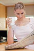 Portrait of a young woman reading the news while having coffee