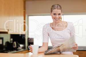 Smiling woman reading the news while having tea