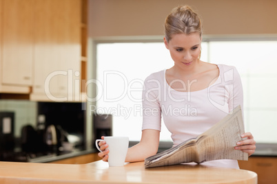 Young woman reading the news while having tea