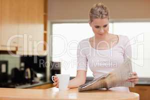 Young woman reading the news while having tea