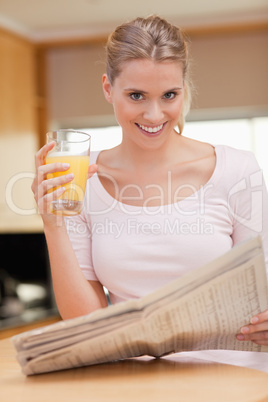 Portrait of a woman reading the news while drinking juice