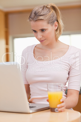 Portrait of a woman using a laptop while drinking juice