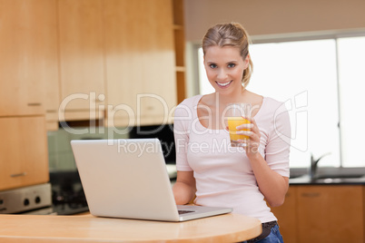 Woman using a notebook while drinking juice