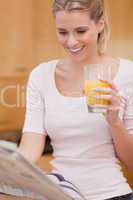 Portrait of a young woman reading the news while drinking juice