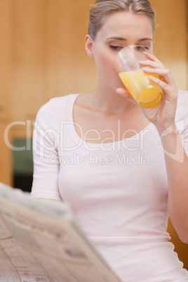 Portrait of a beautiful woman reading the news while drinking ju