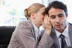 Businesswoman whispering something to her colleague