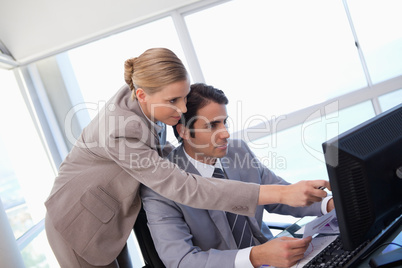 Manager pointing at something to her secretary on a computer