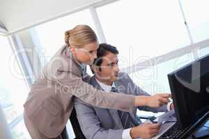 Manager pointing at something to her secretary on a computer