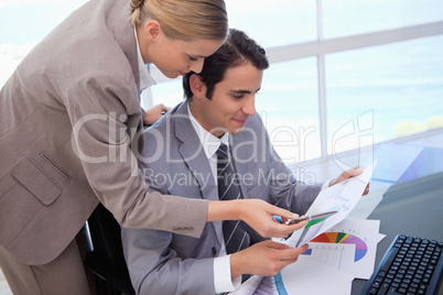 Manager pointing at something to her employee on a graph