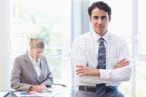 Young businessman posing while his colleague is working