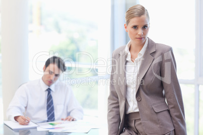 Businesswoman posing while her colleague is working