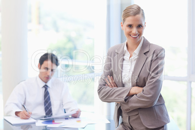 Smiling businesswoman posing while her colleague is working