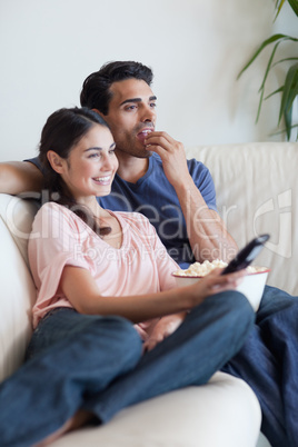 Portrait of a couple watching TV while eating popcorn