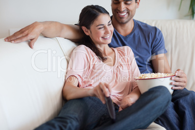 Delighted couple watching TV while eating popcorn