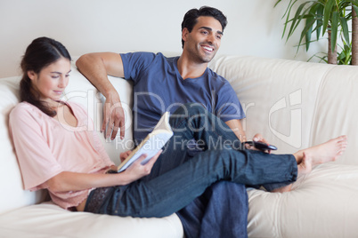 Woman reading a book while her husband is watching television