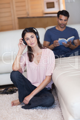 Portrait of a woman listening to music while her husband is read