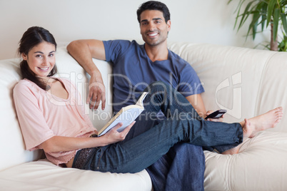 Woman reading a book while her husband is watching TV