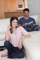 Portrait of a young woman listening to music while her boyfriend