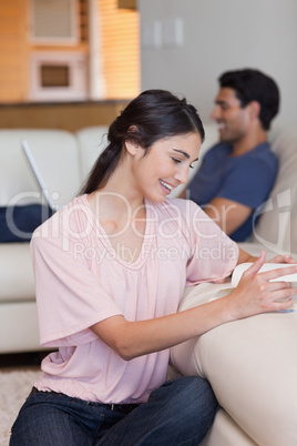 Portrait of a woman reading a book while her boyfriend is using