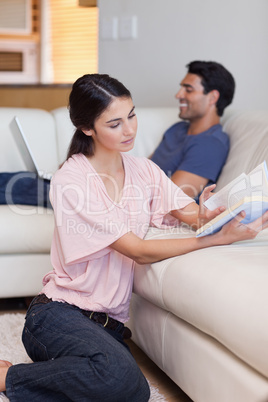 Portrait of a woman reading a book while her fiance is using a l