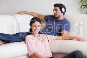Young woman posing while her husband is listening to music