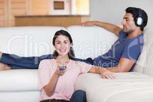 Woman watching television while her husband is listening to musi