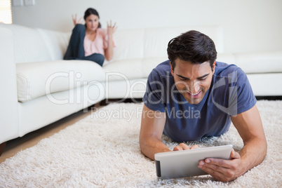 Man using a tablet computer while his girlfriend is getting mad