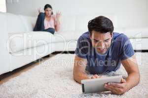 Man using a tablet computer while his girlfriend is getting mad