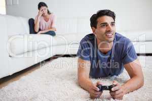 Man playing video games while his girlfriend is getting mad at h