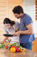 Portrait of a young couple cooking with a pan