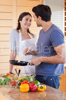 Portrait of a beautiful couple cooking with a pan