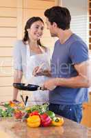 Portrait of a beautiful couple cooking with a pan
