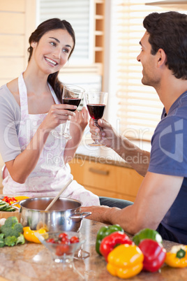 Portrait of a couple having a glass of red wine while cooking