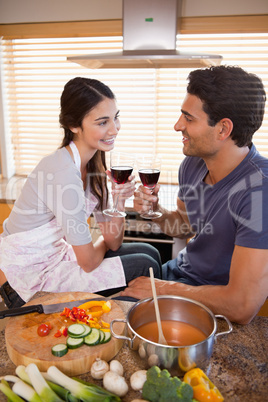 Portrait of a happy couple having a glass of wine while cooking