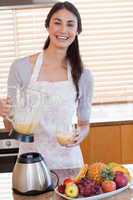 Portrait of a young woman pouring fresh juice in a glass