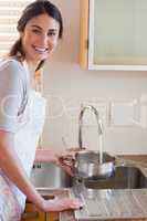 Portrait of a woman pouring water in a sauce pan