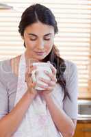 Portrait of a woman smelling a cup of coffee