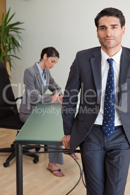 Portrait of a businessman posing while his colleague is working