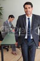 Portrait of a handsome businessman posing while his colleague is