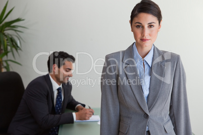 Gorgeous businesswoman posing while her colleague is working